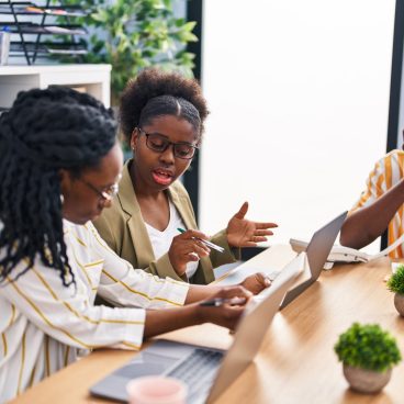 African american friends business workers sitting on table working at office